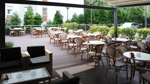 An outdoor patio with wicker furniture, including tables and chairs, and a glass coffee table. - Hotel Orasac (Belgrade)