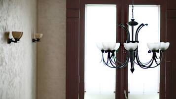A chandelier with multiple arms and light fixtures, a wall-mounted light fixture, and a door with a view to the outside.