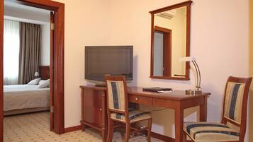 Une chambre d’hôtel comprenant un lit, un bureau avec un ordinateur, une chaise, une lampe de bureau et un miroir.