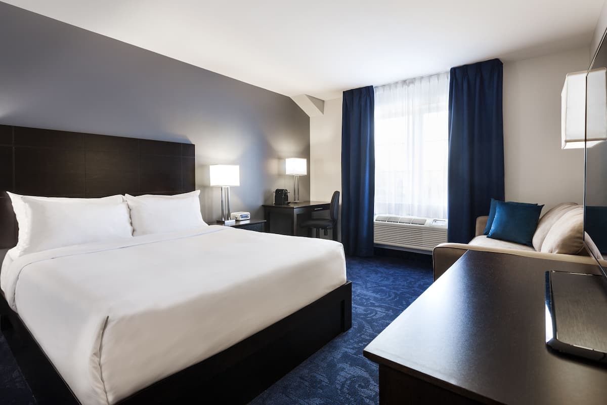 A hotel room with a large bed, a desk, a chair, a desk lamp, a desk lamp, a chair, a desk lamp, a chair, a desk lamp, a chair, a desk lamp, a chair, a desk lamp, a chair, a desk lamp, a chair, a desk lamp, a chair, a desk lamp, a chair, a desk lamp, a chair, a desk lamp, a chair, a desk lamp, a chair, a desk lamp, a chair, a desk lamp, a chair, a desk lamp, a chair, a desk lamp, a chair, a desk lamp, a chair, a desk lamp, a chair, a desk lamp, a chair, a desk lamp, a chair, a desk lamp, a chair, a desk lamp, a chair, a desk lamp, a chair, a desk lamp, a chair, a desk lamp, a chair, a desk lamp, a chair, a desk lamp,