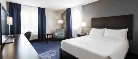 Una habitación de hotel con una cama grande, un escritorio, una silla y una mesita.