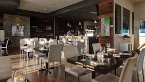 A modern restaurant with a bar area, white furniture, and artwork on the walls. - Imperia Hotel and Suites (Saint-Eustache)