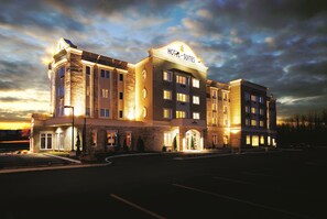 A hotel with a prominent "HOTEL SUITES" sign, multiple floors, and a well-lit entrance.