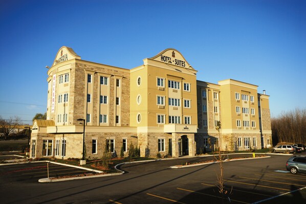 A hotel with a central entrance, multiple floors, and a parking lot.