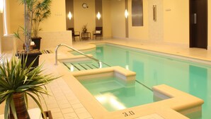 An indoor swimming pool with a tiled floor, a metal ladder, and a potted plant. - Imperia Hotel and Suites (Saint-Eustache)