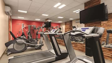 Un gimnasio con cintas de correr, elípticas y equipo de pesas.