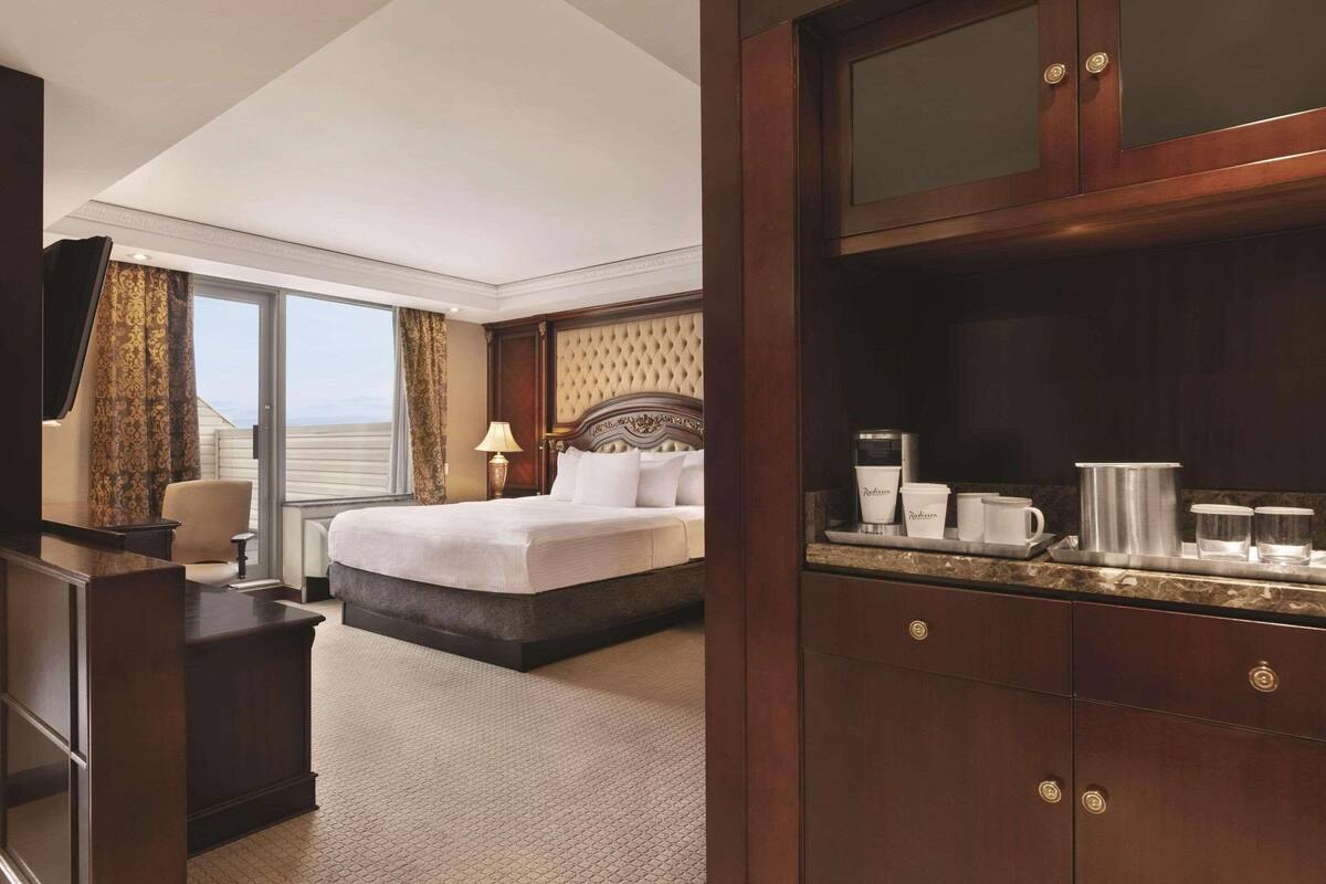A hotel room with a bed, a desk, a dresser, and a minibar.