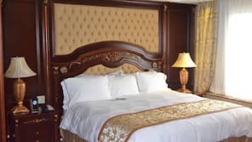 Una cama grande con cabecera capitonada, dos lámparas de noche y una colcha decorativa.