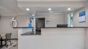 Uma área de recepção com balcão, porta e mesa de check-in.