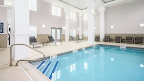 Una piscina con sillones de descanso y barandilla de seguridad.