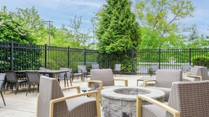 Un patio al aire libre con mobiliario de mimbre, una chimenea de piedra y vistas a un cuerpo de agua.