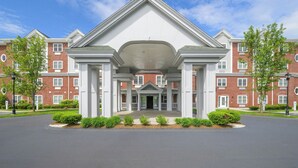 Un edificio de varios pisos con una entrada central, rodeado de muros de ladrillo y columnas blancas.