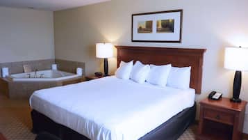 A hotel room with a large bed, a separate bathroom with a bathtub, and a small bedside table with a lamp.