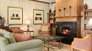 A cozy living room with a fireplace, comfortable seating, and framed artwork on the walls. - Country Inn & Suites by Radisson, Peoria North, IL (Peoria)
