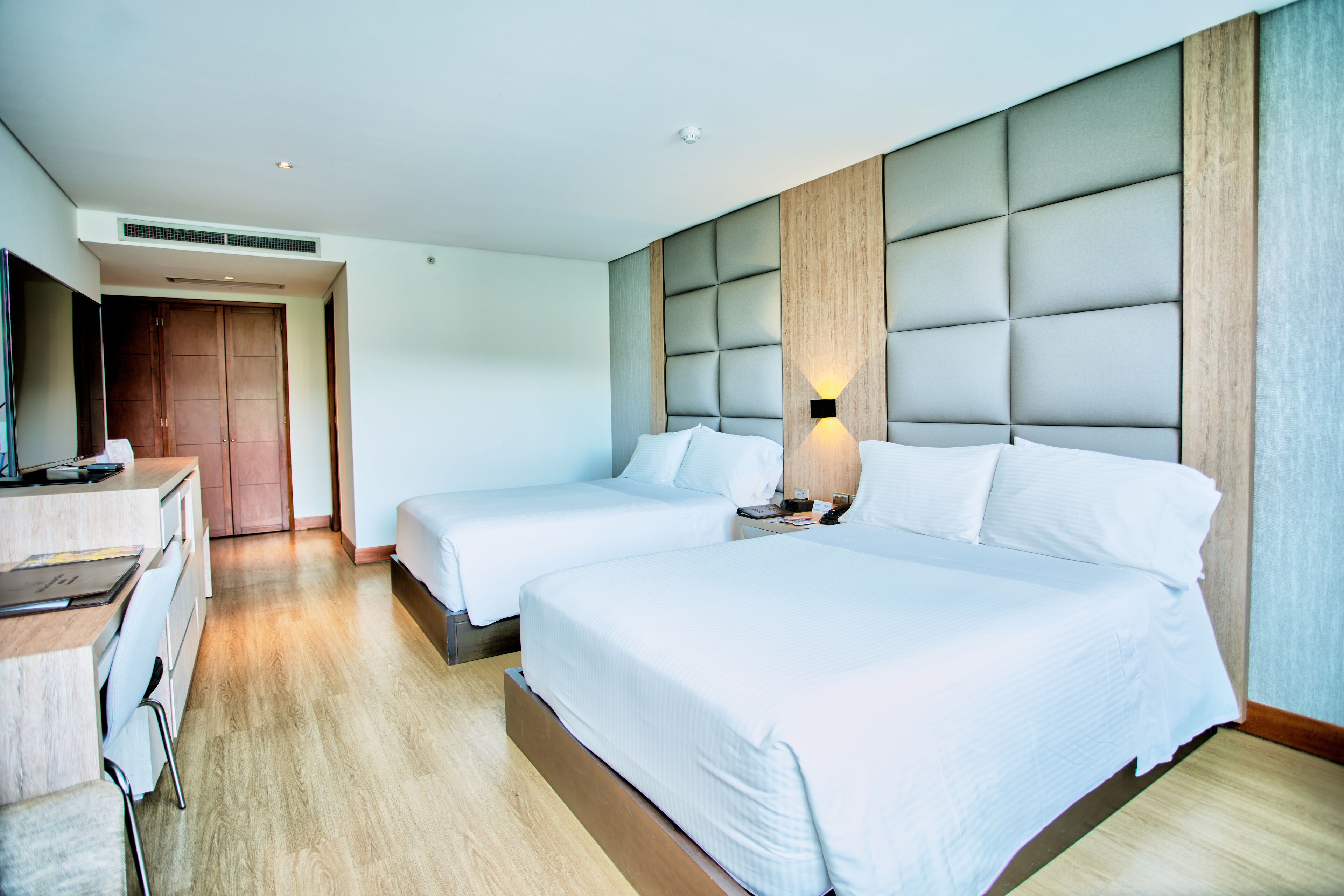 A hotel room with two beds, a desk, and a wardrobe.