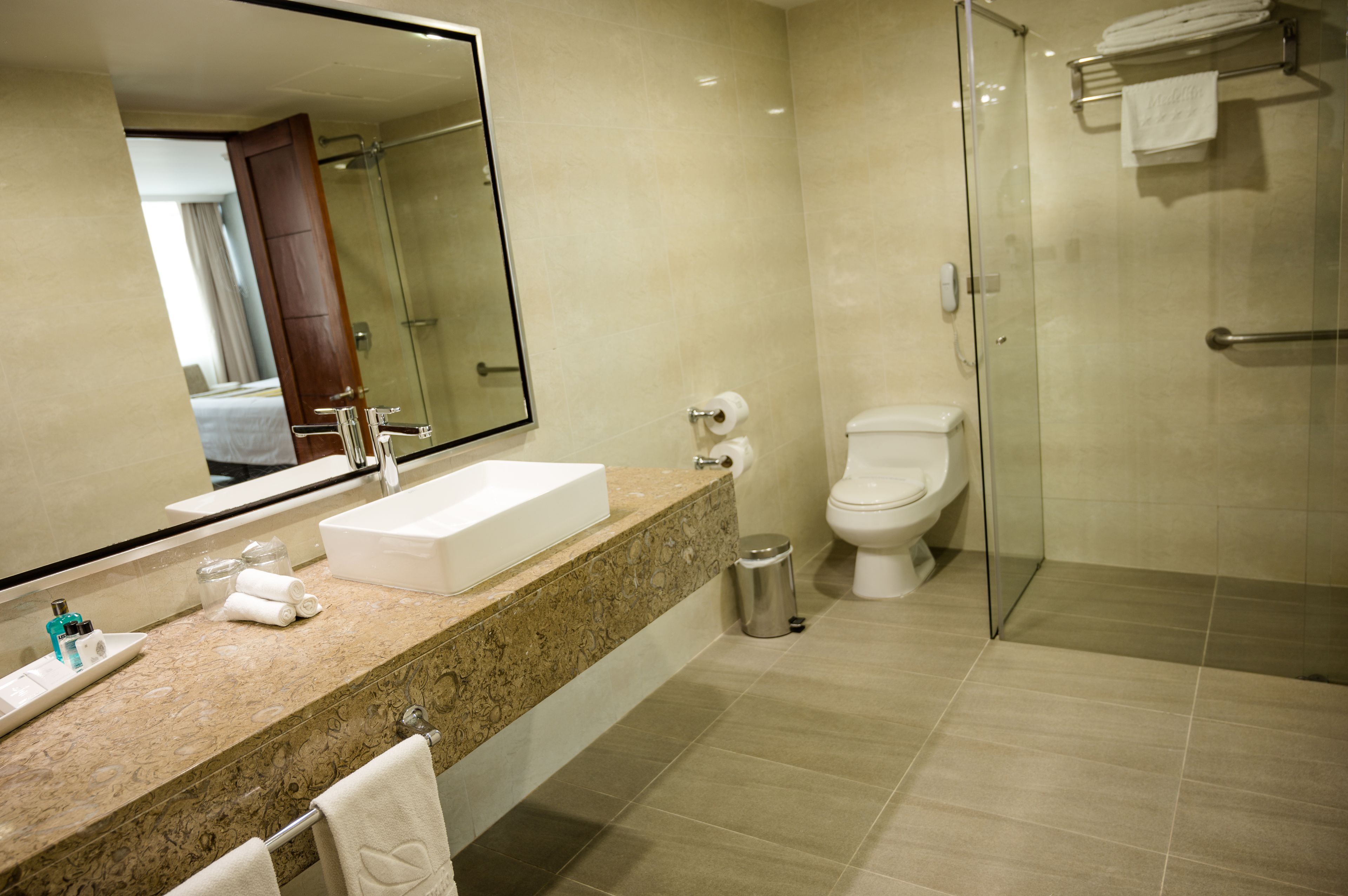 Un bagno moderno con uno specchio grande, un lavabo, un water e un box doccia in vetro.