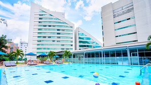 Ein Pool mit Liegestühlen und Sonnenschirmen, umgeben von modernen Gebäuden.