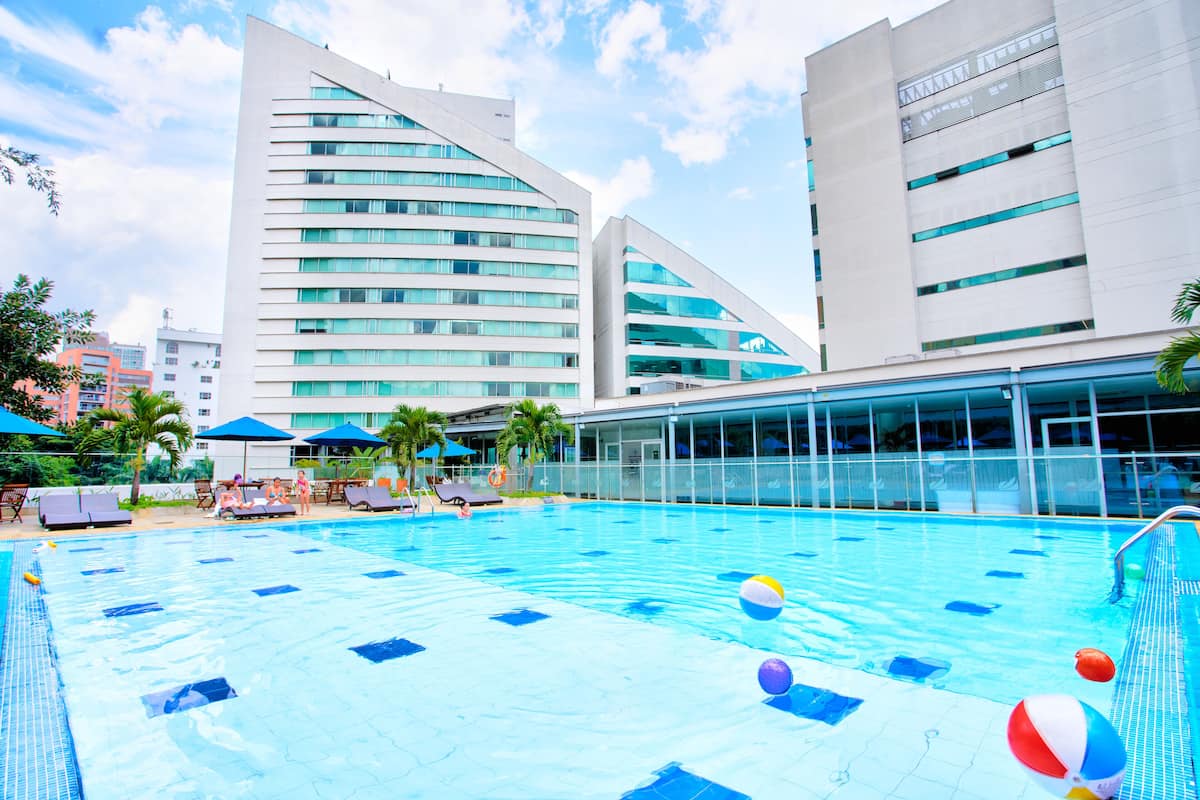 Ein Pool mit Liegestühlen und Sonnenschirmen, umgeben von modernen Gebäuden.