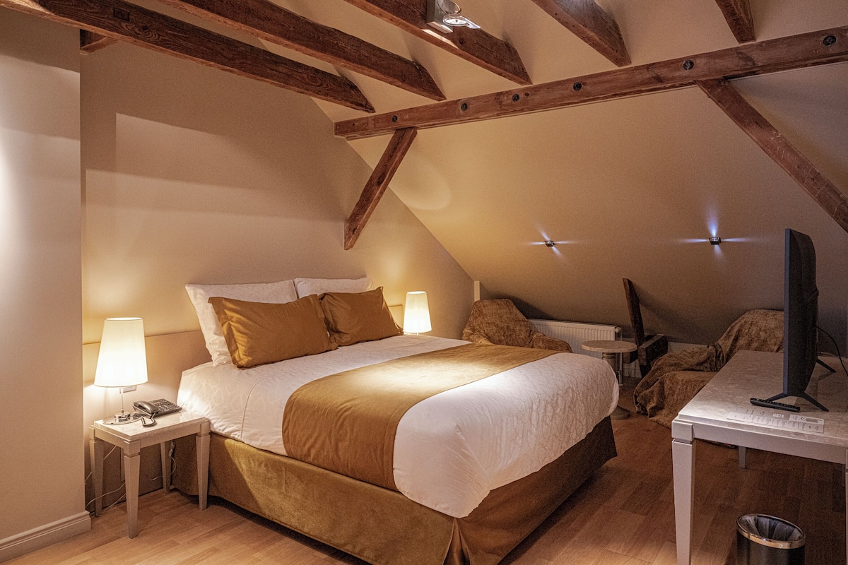 A bedroom with a bed, bedside tables, a desk, and a computer.