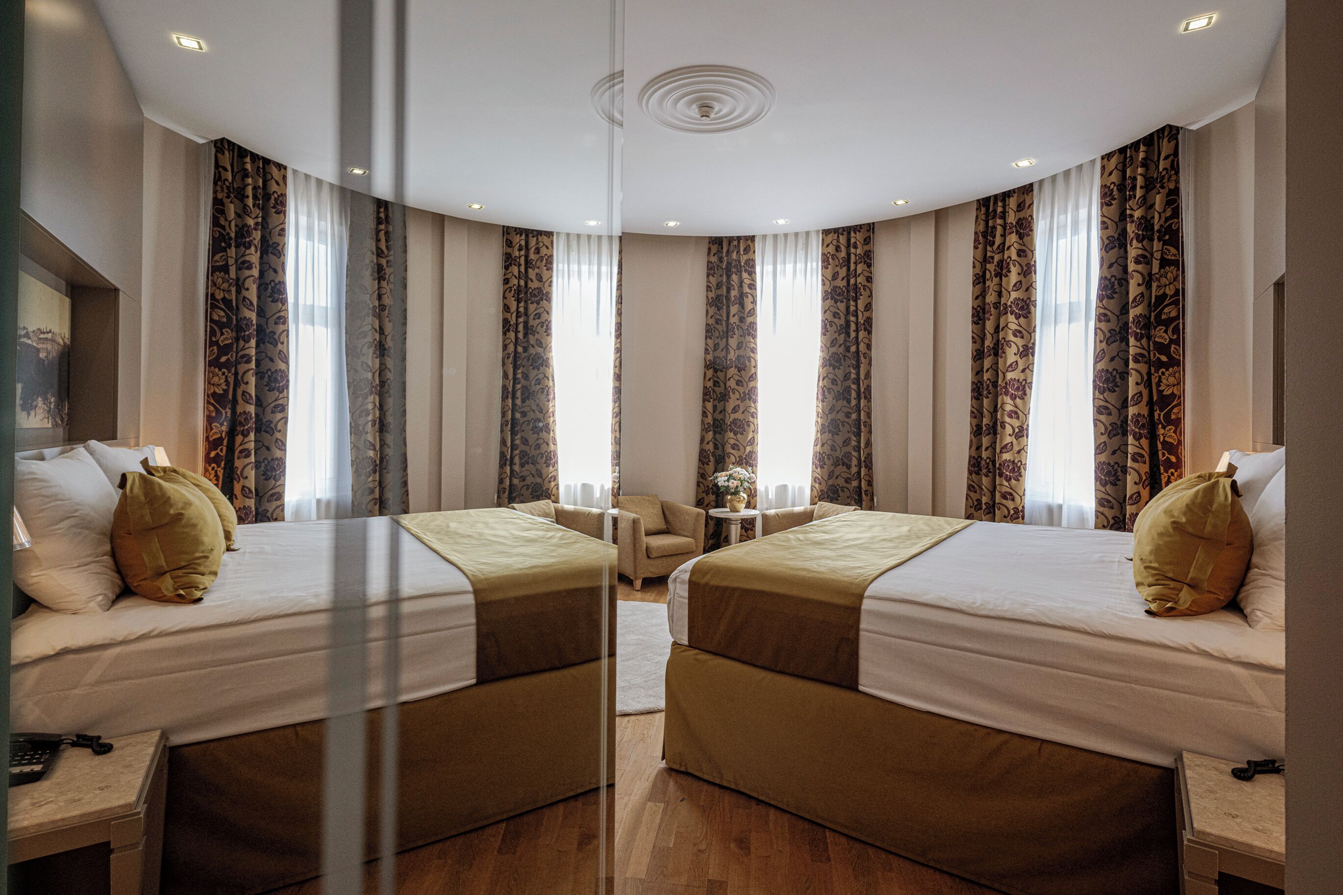 Ein Hotelzimmer mit Spiegel, zwei Betten, einem kleinen runden Tisch und einem Sessel.