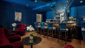 Un espace bar avec des chaises rouges, une table noire et un comptoir où sont exposées des bouteilles.