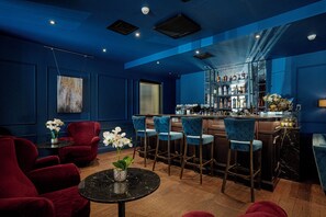 Ein Barbereich mit roten Stühlen, einem schwarzen Tisch und einer Bar, die mit Flaschen bestückt ist.