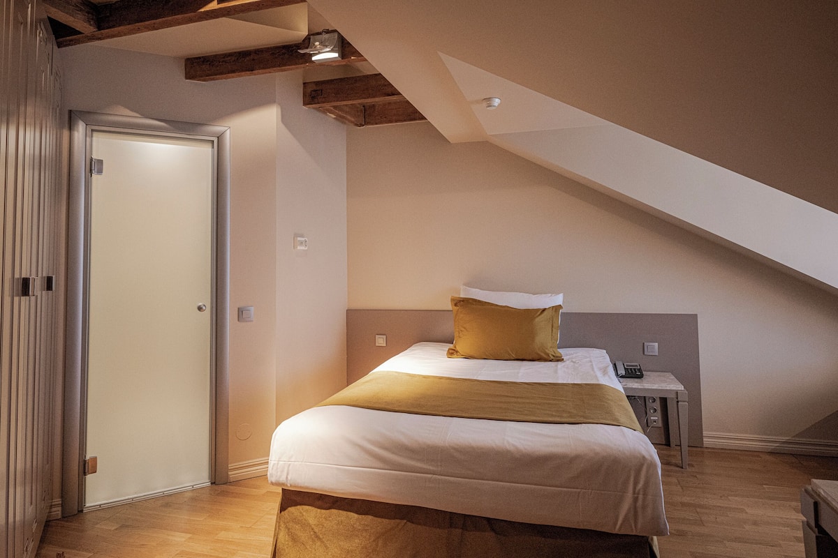 A bedroom with a bed, a desk, and a door.