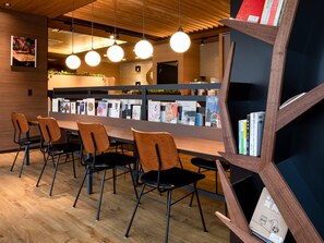 A modern interior with a wooden reception desk, black and orange chairs, and a bookshelf with books. - Comfort Hotel Nara (Nara)