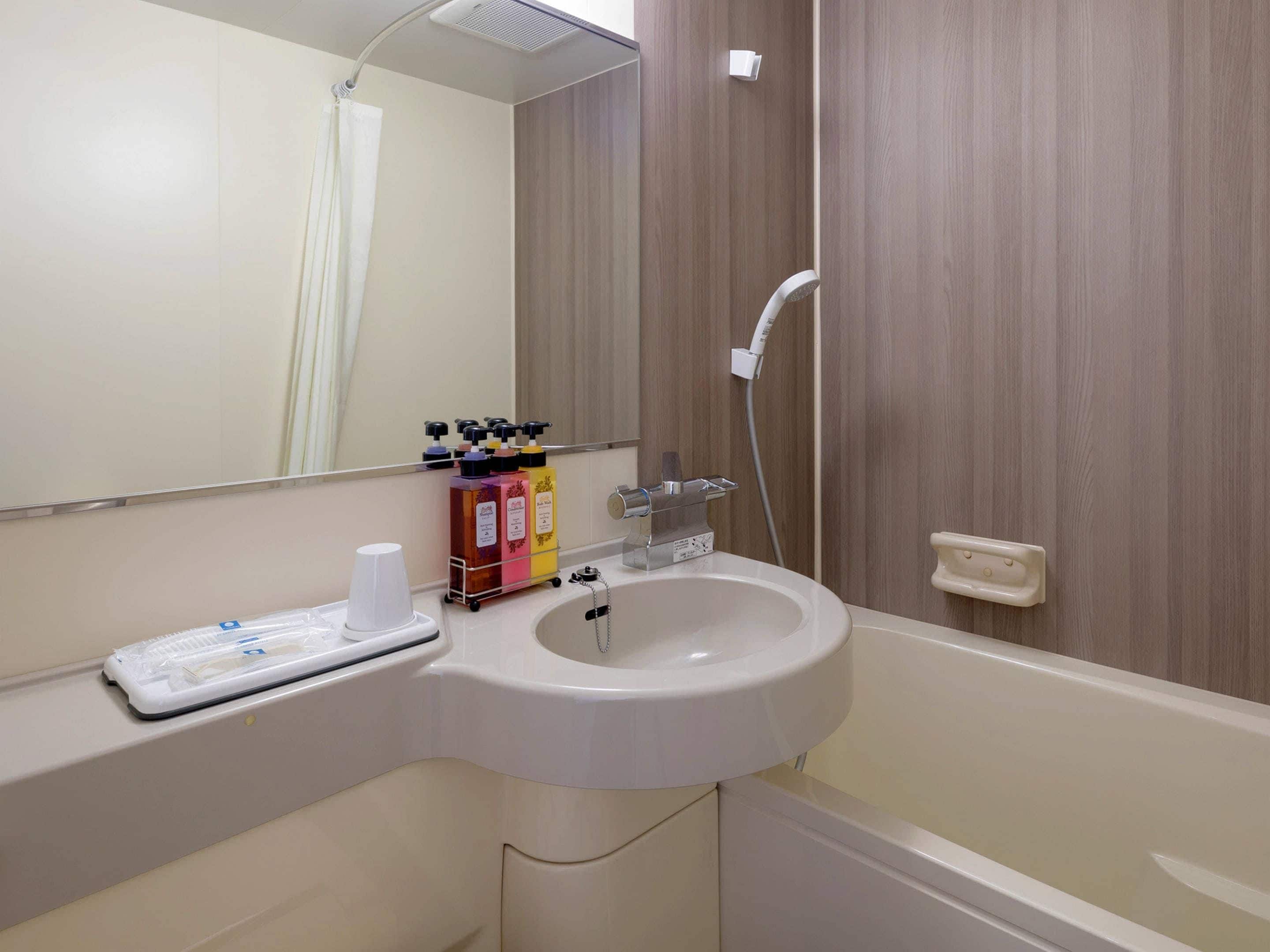 Une salle de bain équipée d’un lavabo, d’un miroir, d’une douche et d’articles de toilette.