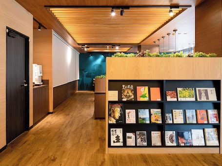 A hallway with wooden flooring, a reception desk with a book display, and a wall with a mural.
