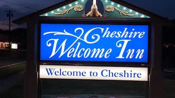 Skilt for Cheshire Welcome Inn med et traditionelt design og oplyst velkomstbesked.