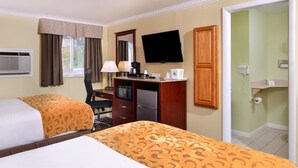 Een hotelkamer met twee bedden, een bureau met televisie, een magnetron en een koffiezetapparaat.