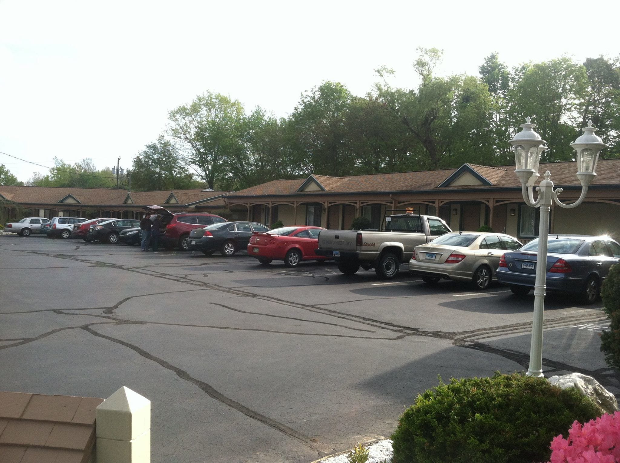 A parking lot with several cars and a truck, a building with a tiled roof, and a street lamp.