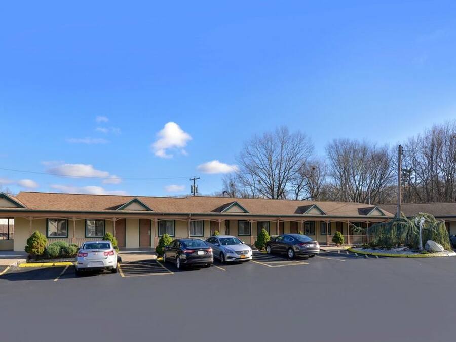 A motel with a parking lot and several cars parked in front.