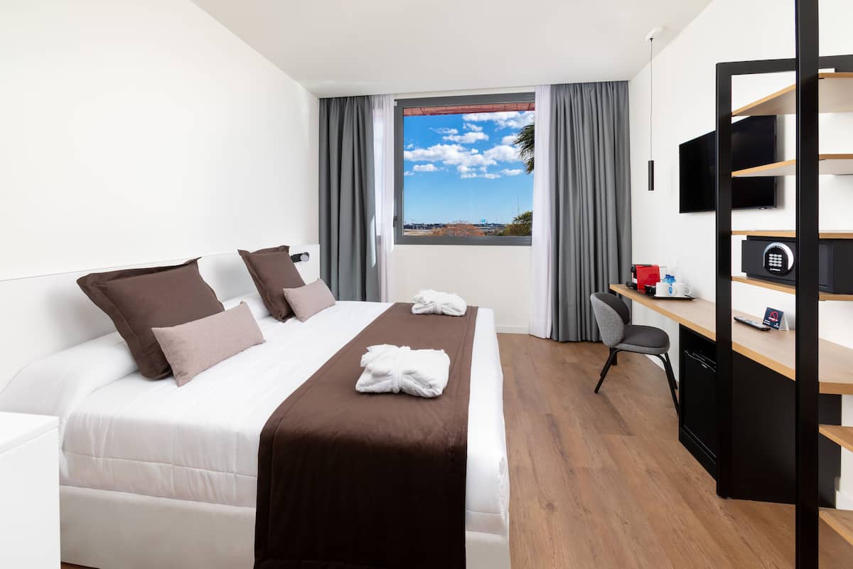 Ein Hotelzimmer mit Bett, Schreibtisch, Fernseher und einem Fenster mit Blick.