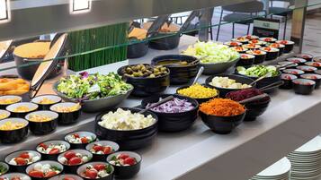 A buffet with various food items in black bowls, including salads, cheeses, and vegetables.