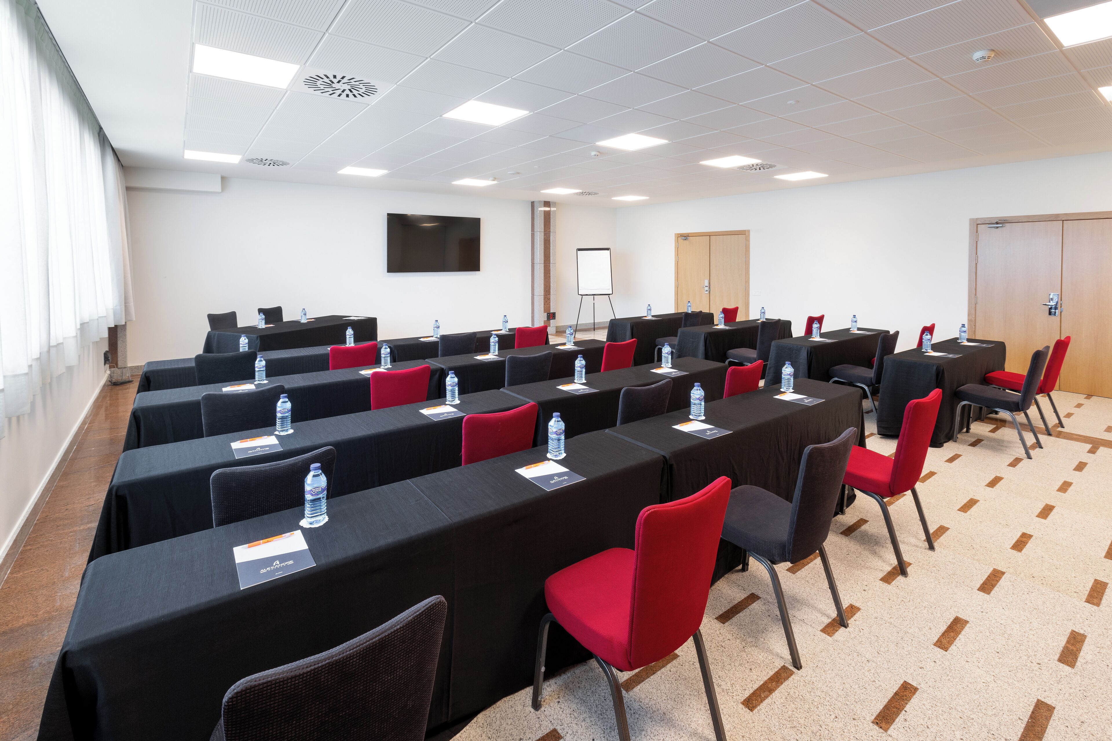 A conference room with multiple tables, chairs, and a whiteboard.