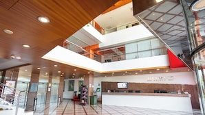 Un hall d’hôtel avec un comptoir d’accueil, des ascenseurs et un escalier.