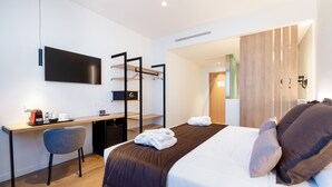 Une chambre d’hôtel moderne équipée d’un lit, d’un bureau, d’une chaise, d’une télévision et d’une armoire.
