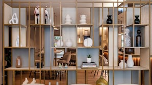 A modern interior with a wooden partitioned shelving unit displaying various decorative items and books.