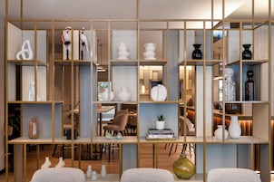 Un interior moderno con una estantería de madera dividida que exhibe varios objetos decorativos y libros.