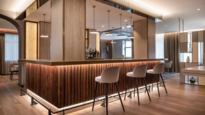 A modern bar area with wooden paneling, pendant lighting, and bar stools.