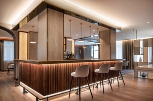 A modern bar area with wooden paneling, pendant lighting, and bar stools.