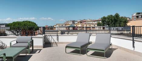 A rooftop terrace with outdoor seating and a view of the cityscape.