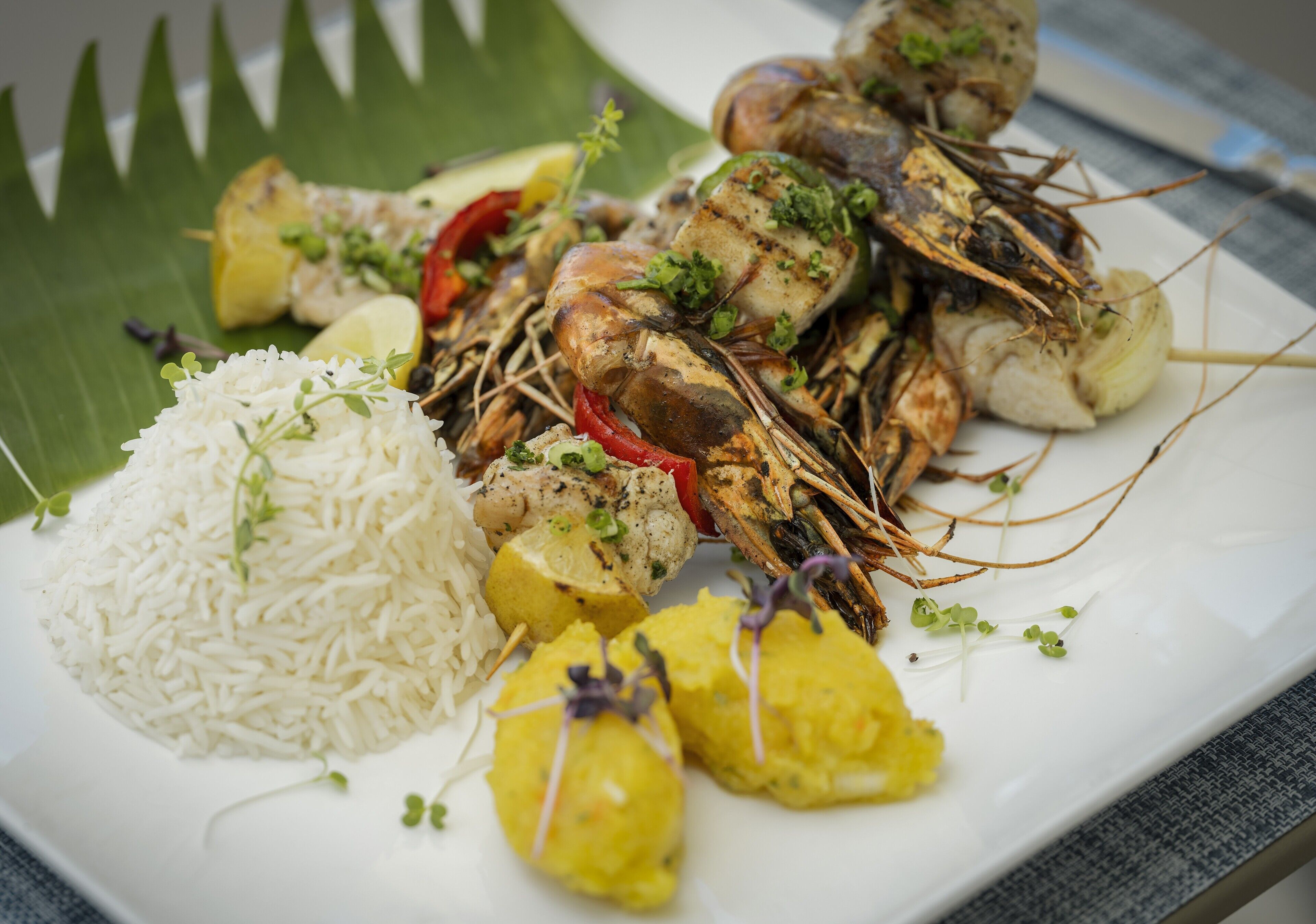 A plate of grilled seafood, rice, and yellow curry.