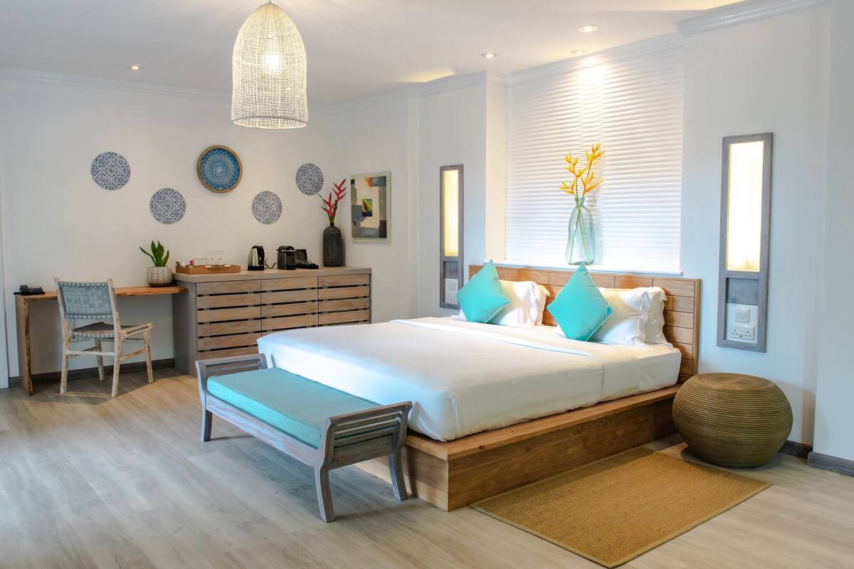 A modern bedroom with a bed, desk, chair, and decorative wall art.