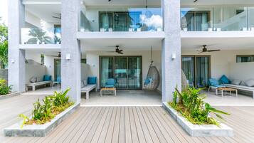 A modern hotel with a wooden deck, outdoor seating, and ceiling fans.