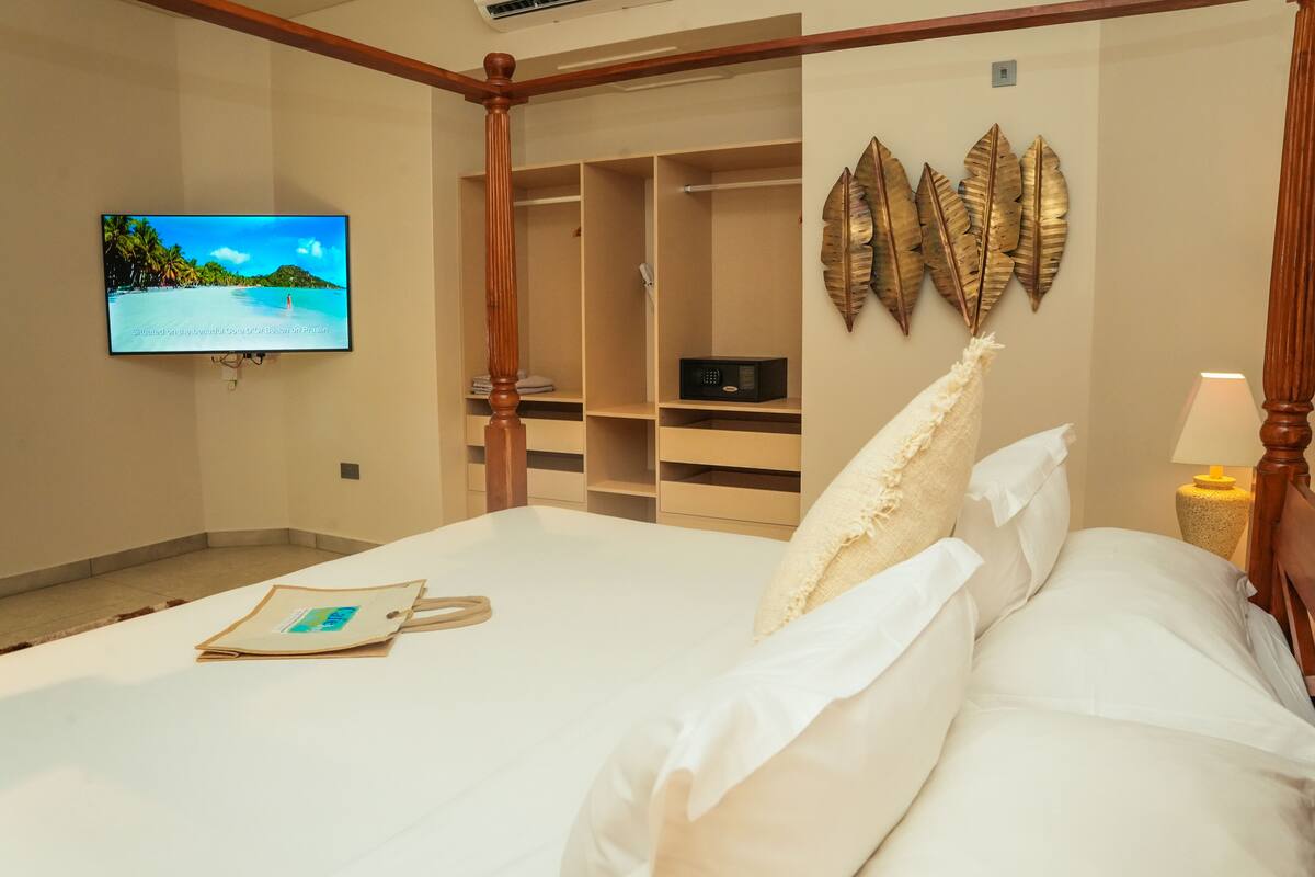 Ein Hotelzimmer mit einem Bett, einem an der Wand befestigten Fernseher, einem Schrank mit Regalen und einem dekorativen Wandbild.