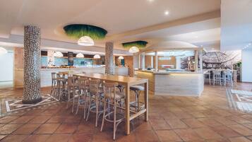 A spacious indoor area with a long wooden table and chairs, a counter with a sign, and a unique ceiling design.