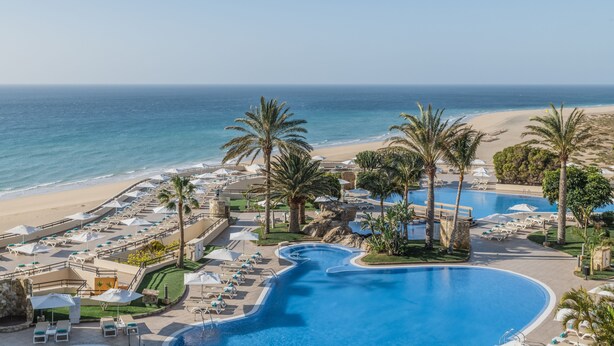 A resort with a large swimming pool, beachside lounge areas, and palm trees. - Iberostar Waves Playa Gaviotas -All Inclusive (Pajara)